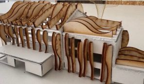 Side view of the 1:200 Maison Peplum model with tall curved timber fins standing before the white card wall and wavy fins over the roof.